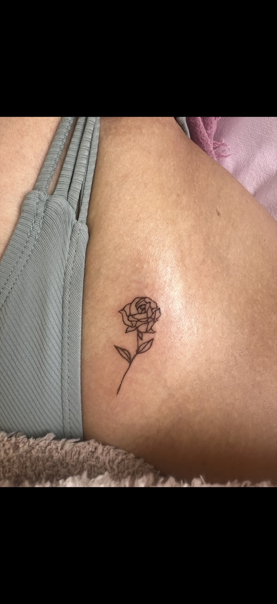Tiny fine-line rose tattoo on the hip by Memi Wilson in Honolulu