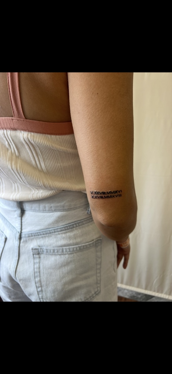Tiny Roman numeral date tattoo on the arm by Memi Wilson in Honolulu