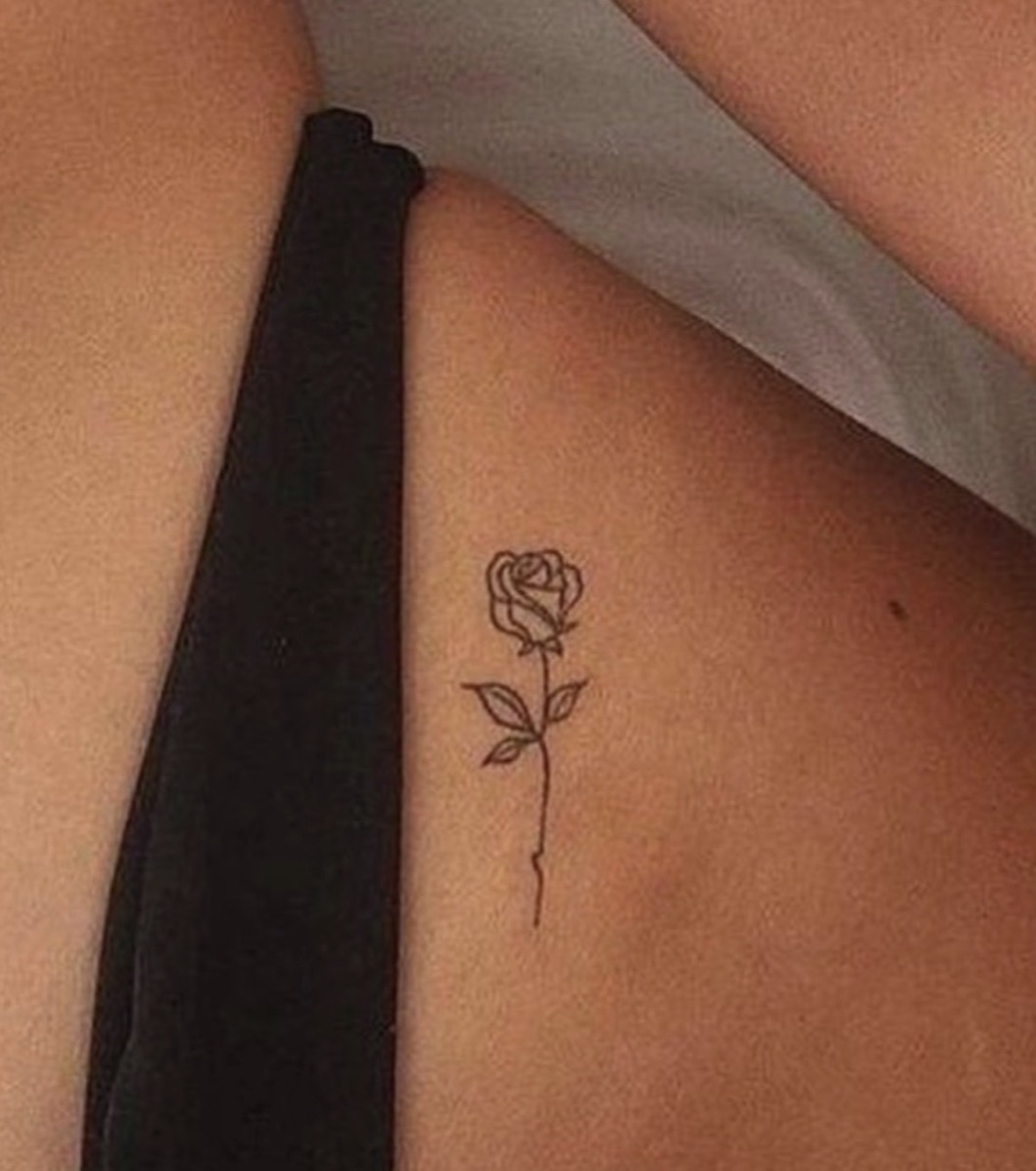 Tiny fine-line rose tattoo on the torso by Memi Wilson in Honolulu