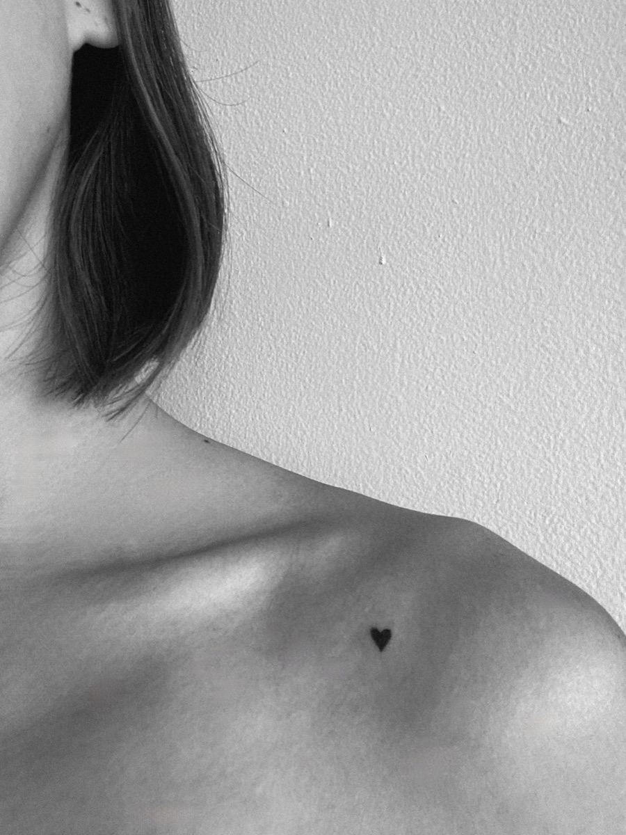 Tiny fine-line heart tattoo on the collarbone by Memi Wilson in Honolulu